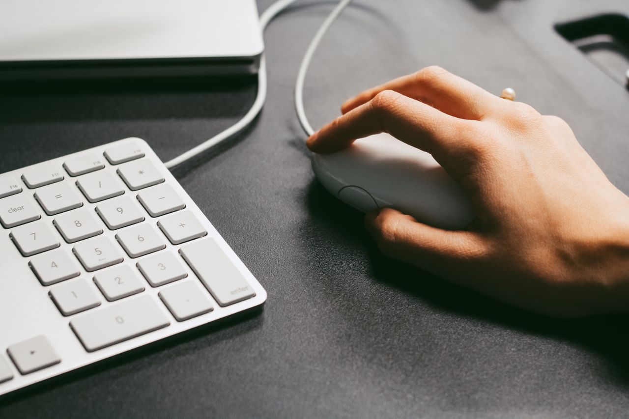 Hand on a computer mouse beside a keyboard