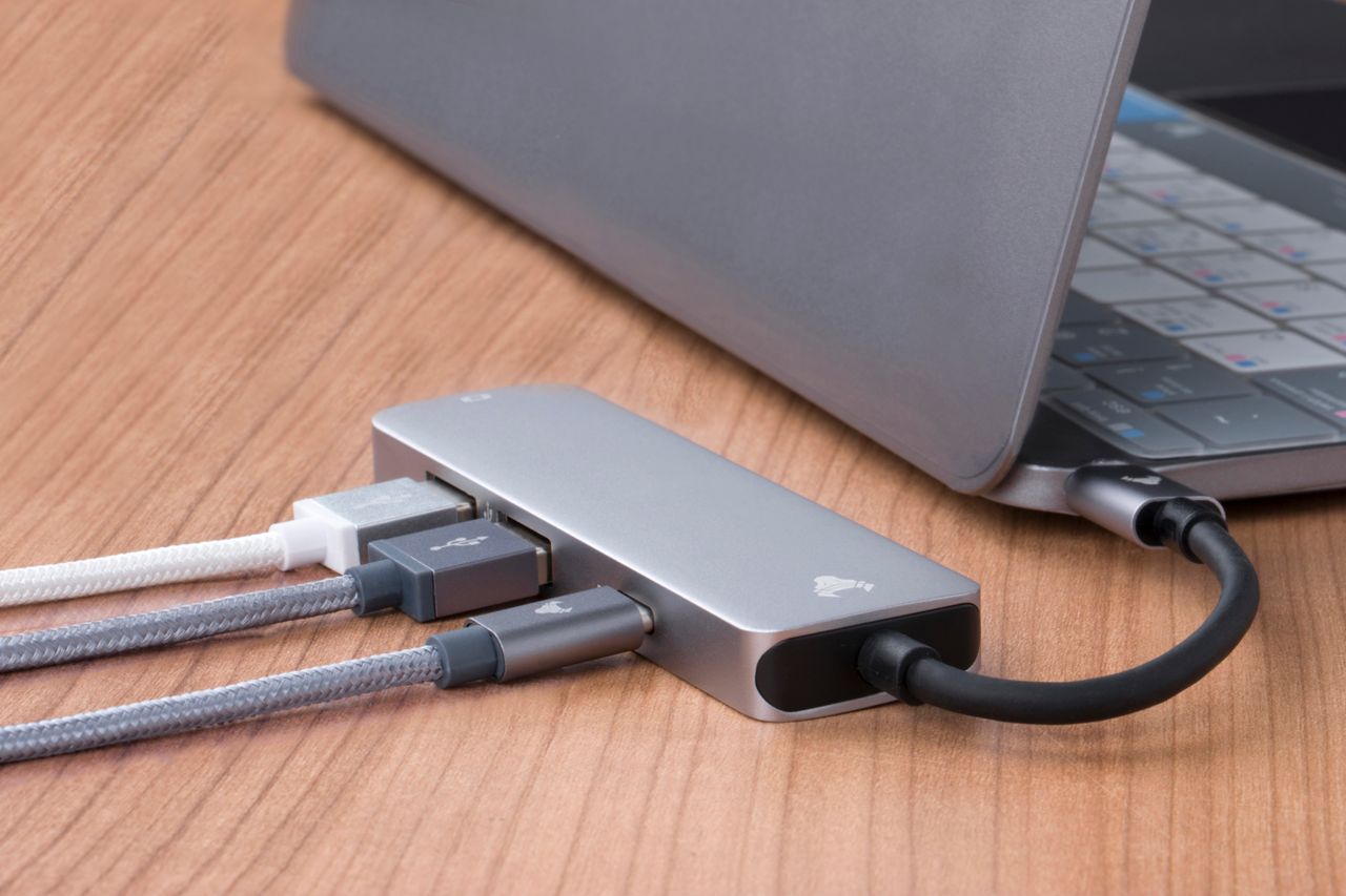 USB-Hub mit angeschlossenen Kabeln neben einem Laptop