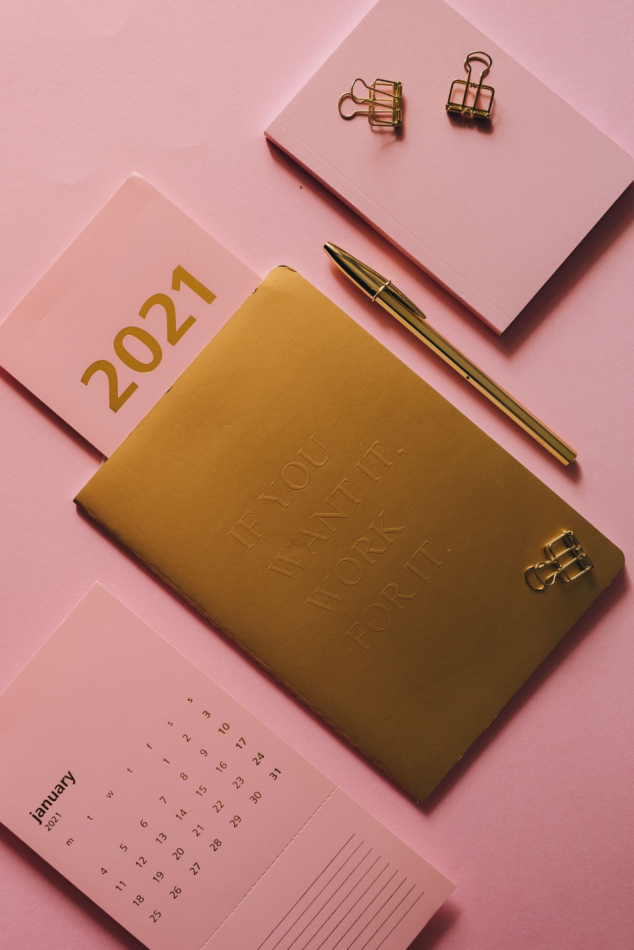 Kalender und Notizbuch auf einer rosa Fläche